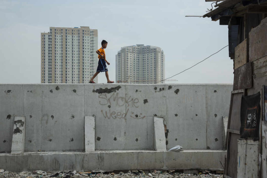 JAKARTA, INDONESIE - 27 AVRIL : Un garçon indonésien marche le long d'une section nouvellement construite de la digue, le 27 avril 2017 à Jakarta, en Indonésie. Jakarta, l'une des villes les plus densément peuplées au monde, est également l'une des villes qui s'affaissent le plus rapidement sous le poids d'un développement incontrôlé et de la montée du niveau de la mer causée par le réchauffement climatique. Les experts estiment que si rien n'est fait, certaines parties de Jakarta s'enfonceront de cinq mètres d'ici 2025. Le gouvernement propose donc un projet de 40 milliards de dollars pour s'attaquer au problème en construisant une digue de 15 miles et 17 îles artificielles autour de la côte septentrionale de Jakarta. La digue le long de la côte et dans la baie de Jakarta a commencé à être une solution immédiate, tandis que l'administration du président Widodo continue à travailler sur les détails du grand projet surnommé Garuda. L'augmentation des inondations et des tempêtes violentes dues à la hausse des températures et au changement climatique a menacé les habitants de la côte nord de Jakarta, pour la plupart pauvres, de perdre leurs maisons. Des rapports indiquent que le problème a été exacerbé par la surutilisation massive des eaux souterraines, qui a provoqué des affaissements. (Photo par Ed Wray/Getty Images)