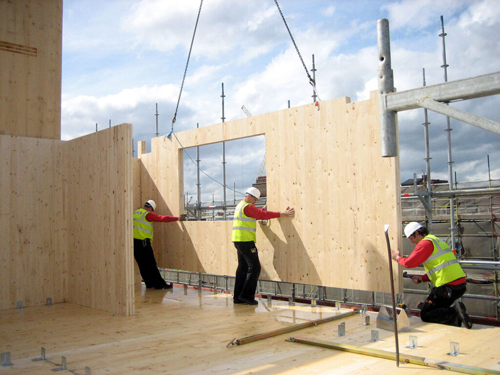 Construction en bois, ouvriers avec casques, montage de panneaux, chantier de jour.